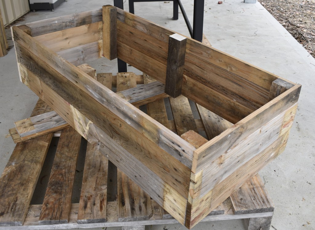 An image of a raised garden bed made from shipping pallets resting on top of a shipping pallet.