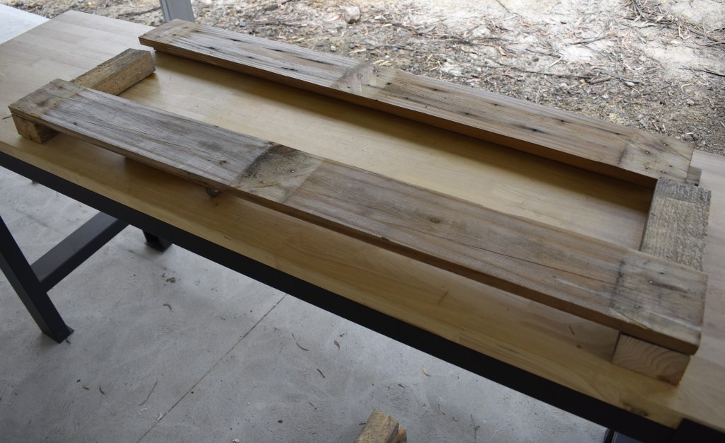 Two beams laid down with the longer side planks being attached. 